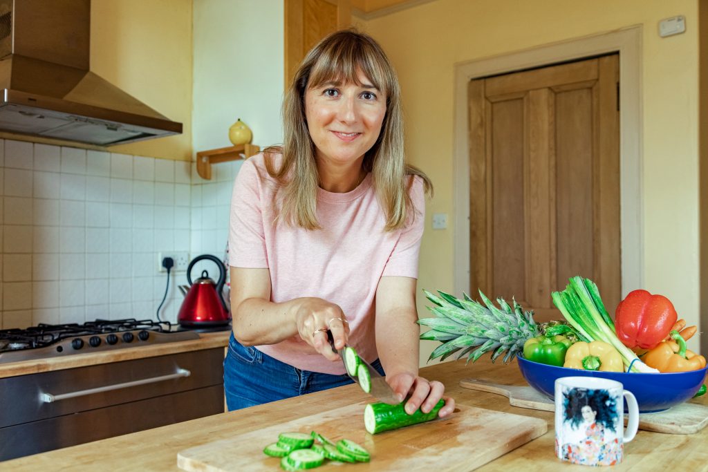 health coach cuts cucumber in a kitchen